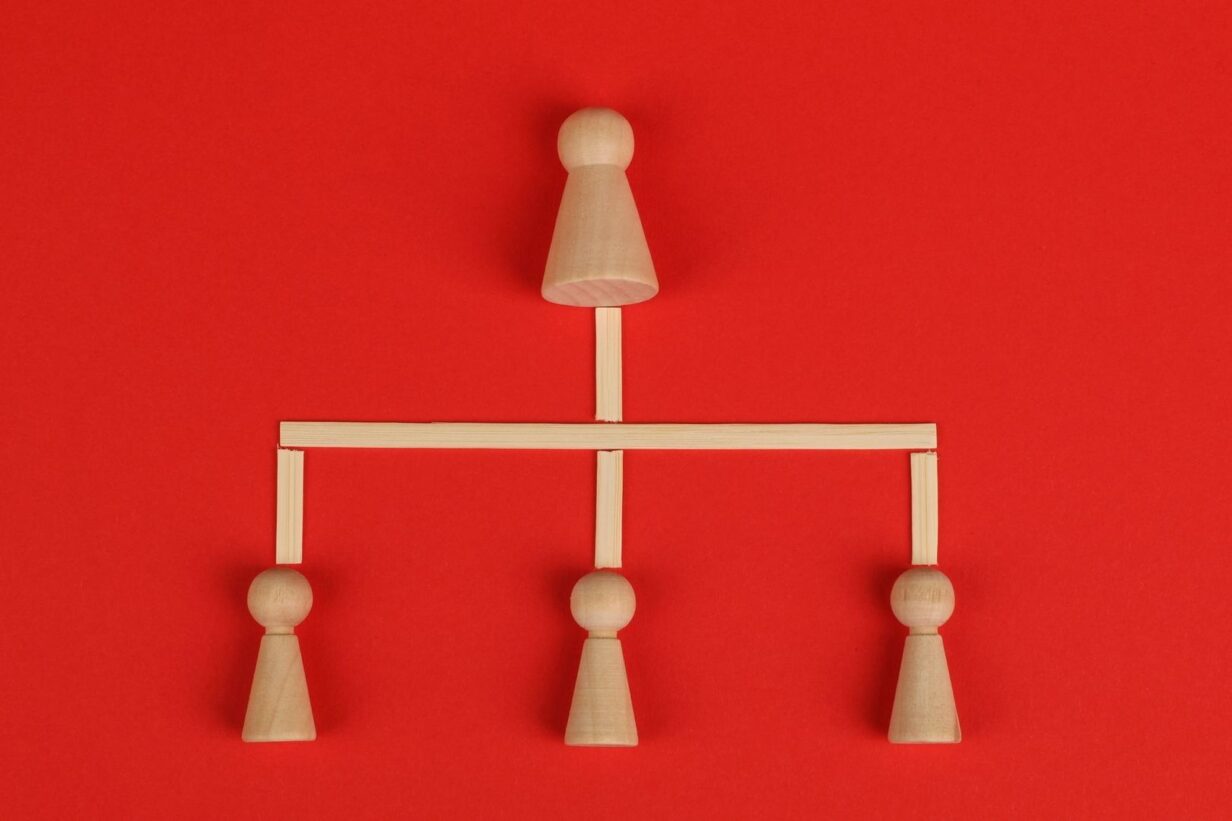 Träfigurer i en hierarkisk relation på röd bakgrund
