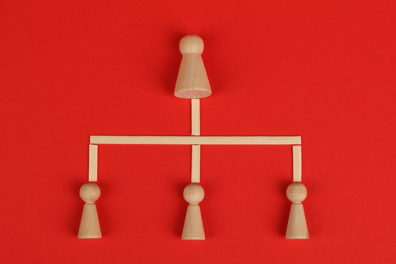 Träfigurer i en hierarkisk relation på röd bakgrund
